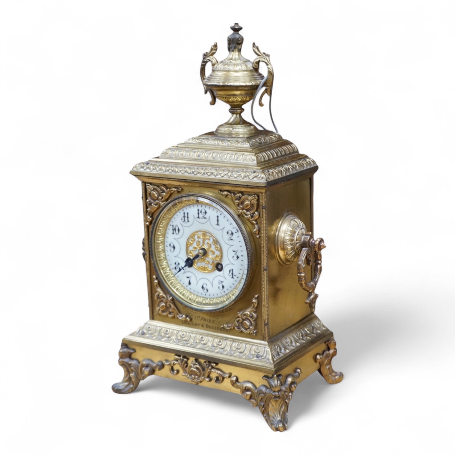 A decorative brass mantel clock with urn surmount, with 1st prize engraved panel, 41cm high